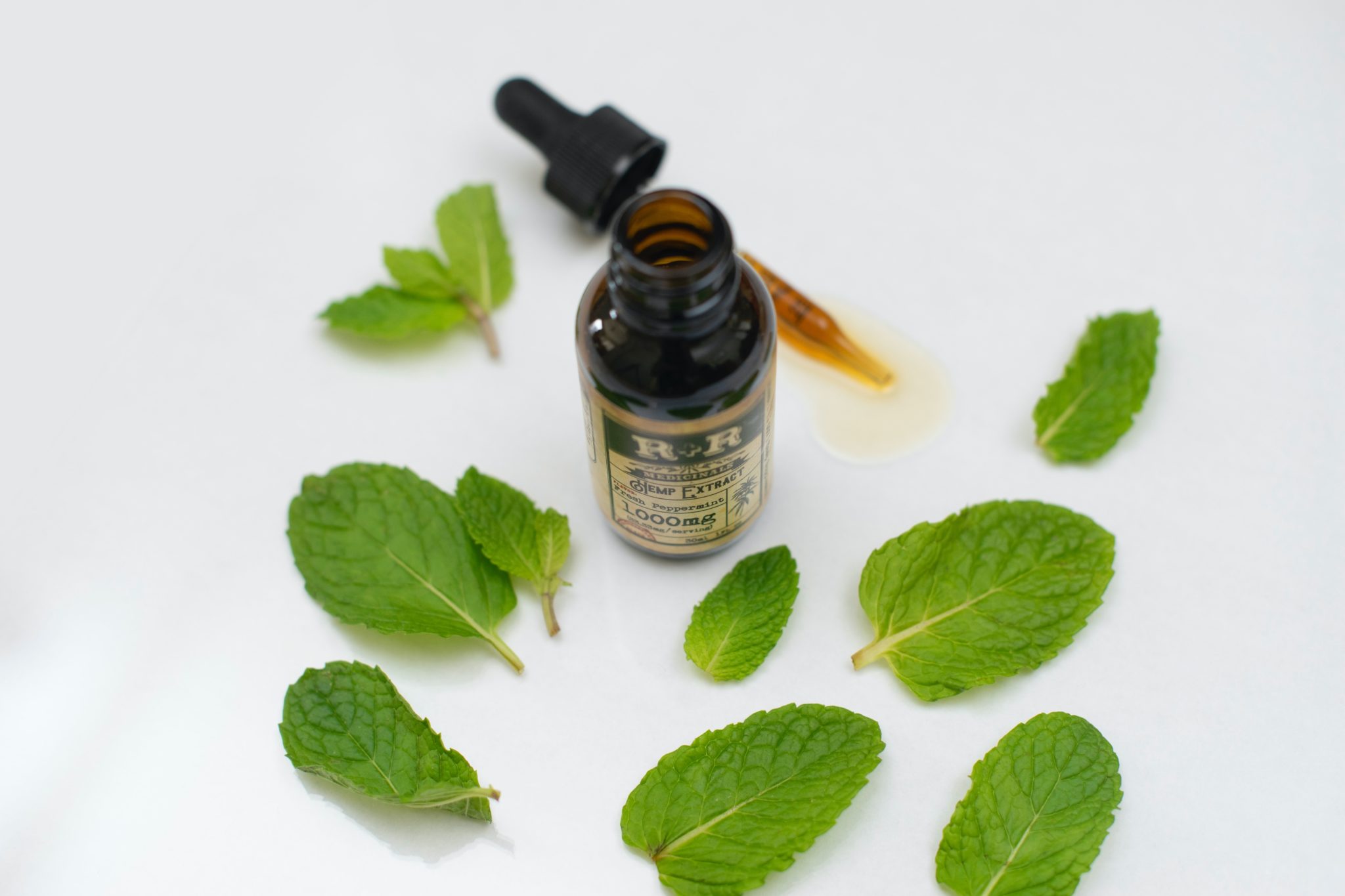 Bottle of peppermint oil surrounded by mint leaves
